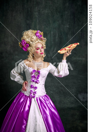 Beautiful woman with bright make up looking at seductive huge American hot dog with souses against vintage background. 109024158