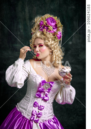 Beautiful woman, queen with bright make-up and retro hairstyle eating cold and sweet ice cream, tasty dessert against vintage background. Beautiful woman, queen with bright make-up and retro hairstyle eating cold and sweet ice cream, tasty dessert against vintage background. 109024188