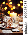 Gingerbread house on table. Defocused lights of Christmas garland. Evening in the living room. Holiday mood.  109026935