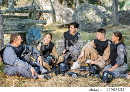 Positive paintball players sitting on battleground and chatting Positive paintball players sitting on battleground and chatting 109028334