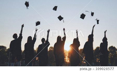 Silhouettes of Happy college graduates tossing their caps up at sunset. Silhouettes of Happy college graduates tossing their caps up at sunset. 109028577