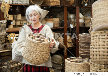Elderly woman choosing basket in store 109028622
