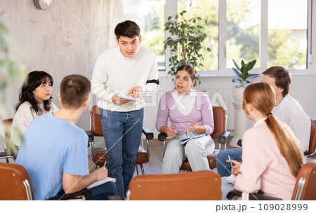 Young male tutor teaching group of students in college 109028999