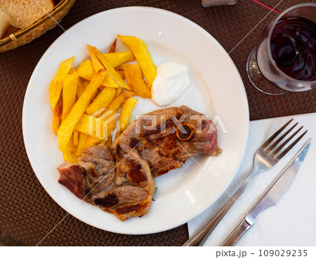 Lamb palpis with french fries potatoes and wine on white plate. Closeup 109029235