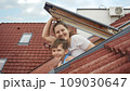 Happy smiling mother with son opens attic windows and looks outdoor. Concept of family happiness, parents with kids, moving to a new house. 109030647