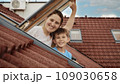 Delight of a mother and her son as they open attic windows and enjoy the view outside, illustrating the idea of family joy, parents sharing moments with their kids, and the excitement of relocating to 109030658