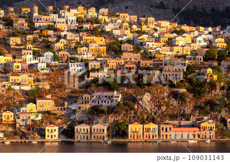 Colorful houses on the slopes of the mountains on Symi island at sunset. 109031143