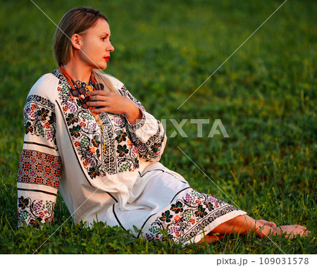 Embroidered and unique petticoat, a girl walks barefoot in the field in an embroidered shirt. Embroidered and unique petticoat, a girl walks barefoot in the field in an embroidered shirt. 109031578
