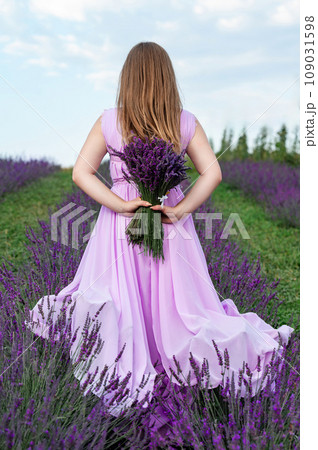 A bouquet of lavender and a girl in a purple dress, back view of the girl. A bouquet of lavender and a girl in a purple dress, back view of the girl. 109031598