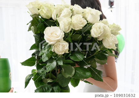 The girl holds a large bouquet of white roses in her hands. 109031632