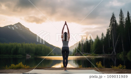 A woman doing a handstand on a yoga mat, with a peaceful, serene setting in the background 109031989