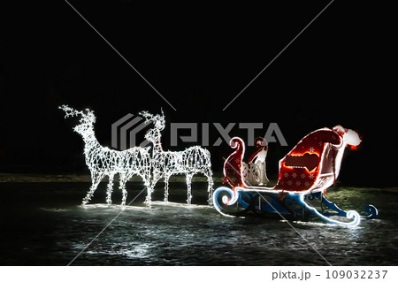 Glowing Christmas reindeer and sleigh of Santa Claus. Street New Year decor. 109032237