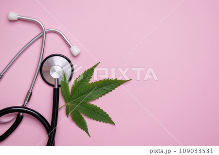 Medical cannabis leaf near and stethoscope top view on pink background. Hemp alternative medicine concept. Medical cannabis leaf near and stethoscope top view on pink background. Hemp alternative medicine concept. 109033531