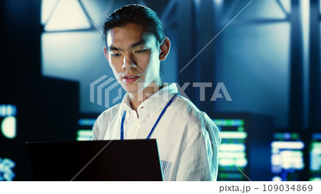 Skillful employee walking through data center systems providing processing resources for different workloads. Admin diagnosing server racks tasked with solving complex operations Skillful employee walking through data center systems providing processing resources for different workloads. Admin diagnosing server racks tasked with solving complex operations 109034869