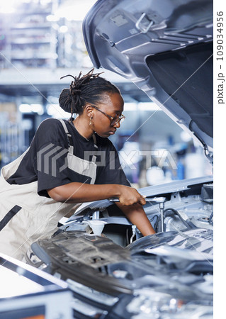 Repair shop technician examines defective car battery using advanced mechanical tools, ensuring peak automotive performance. Diligent worker in garage workplace conducts routine vehicle checkup 109034956