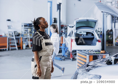 Knowledgeable repair shop employee uses augmented reality to visualize car mechanical parts in order to mend them. Technician using AR technology while working on defective vehicle fuel tank 109034980