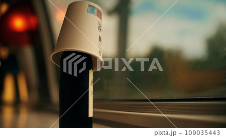 Putting a paper cup on the top of the bottle of red wine while traveling by train in France 109035443
