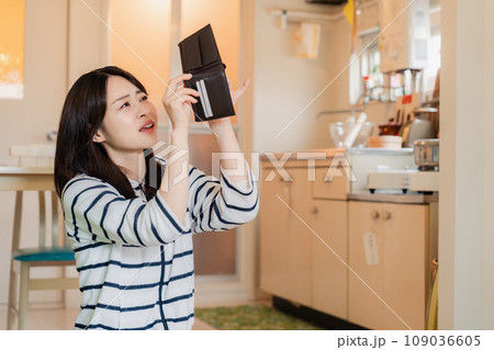 財布の中を確認して落ち込む若い女性 109036605