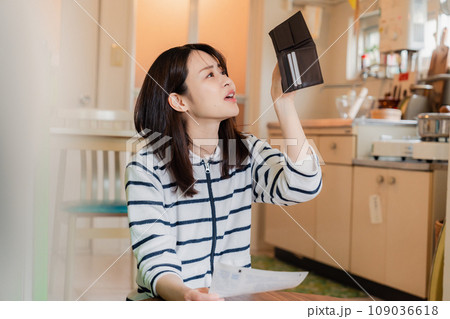 財布の中を確認して落ち込む若い女性 財布の中を確認して落ち込む若い女性 109036618