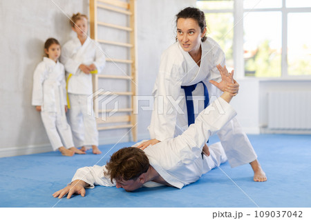 Concentrated woman practicing armlock in sparring with husband at karate training Concentrated woman practicing armlock in sparring with husband at karate training 109037042