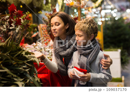 Woman with preteen son looking for potted plants at Christmas street market 109037170