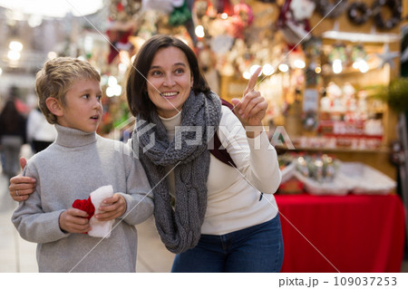 Tween boy with mother choosing Xmas decorations on street fair 109037253
