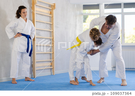 Children with parents practicing judo together on sports mats 109037364