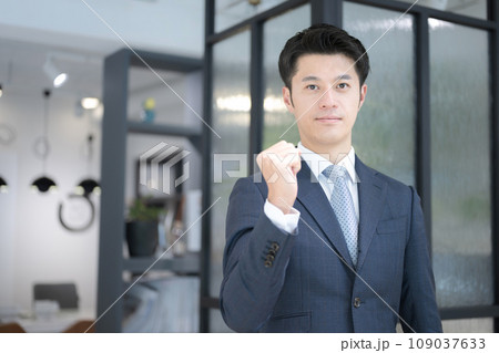 オフィスで立つ笑顔の若いガッツポーズのビジネスマン エグゼクティブな雰囲気 オフィスで立つ笑顔の若いガッツポーズのビジネスマン エグゼクティブな雰囲気 109037633