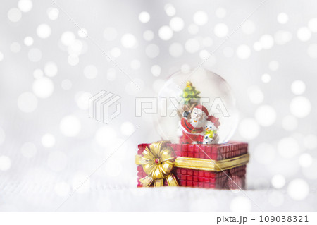 Christmas balls, Santa Claus in a Snow globe, and Pine cones on a Cream-Colored Cloth, set Against a Red Background and exquisite bokeh. New Year Celebration Atmosphere, about of Important day. 109038321