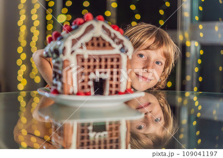 Immerse in festive delight as a boy crafts boy crafting an unconventional gingerbread house, infusing Christmas with unique creativity and festive cheer. A sweet scene of seasonal bonding and culinary 109041197