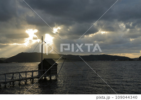 東郷湖の四ツ手網が雲間から差し込む光に照らされる神秘的な風景 東郷湖の四ツ手網が雲間から差し込む光に照らされる神秘的な風景 109044340