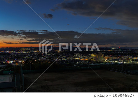 京都木津　城山台で生駒山へ沈む夕日　街灯りに照らされた木津の街と残照⑦ 109046927