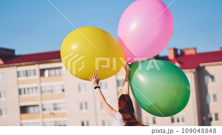 A girl happily poses with large with colorful balloons in the city. 109048848