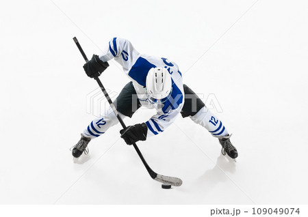 Top view. Competitive young man, hockey player in motion, playing, training on rink against white studio background Top view. Competitive young man, hockey player in motion, playing, training on rink against white studio background 109049074