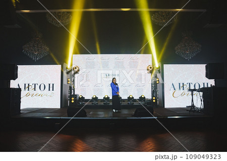 attractive woman in blue jacket on the stage in front of the big screen attractive woman in blue jacket on the stage in front of the big screen 109049323