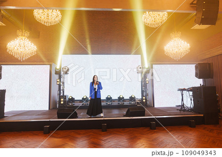 attractive woman in blue jacket on the stage in front of the big screen attractive woman in blue jacket on the stage in front of the big screen 109049343
