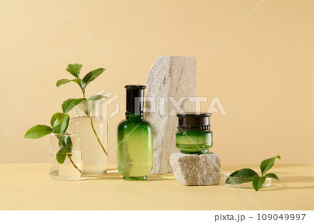 Set of skin care beauty product packaging decorated with gray stones and green tea ingredient on beige background. Bottle and jar without label for design, product presentation 109049997