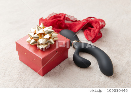 Black vibrator, red lingerie and red gift box with golden bow on the white fur background Black vibrator, red lingerie and red gift box with golden bow on the white fur background 109050446