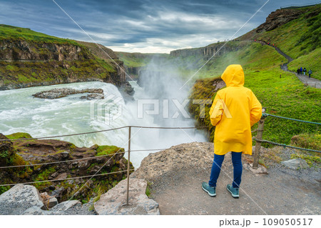 Female tourist enjoying on viewpoint of Gullfoss waterfall with hvita river flowing in canyon at Iceland 109050517