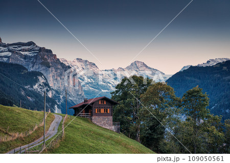 View from Wengen mountain village with Jungfrau and wooden cottage on hill in the evening at Switzerland View from Wengen mountain village with Jungfrau and wooden cottage on hill in the evening at Switzerland 109050561