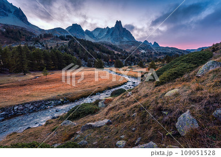 Sunset over Claree Valley with Main De Crepin peak and river flow through in larch forest during autumn at French Alps, France 109051528