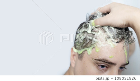 Man does head scrub. Dark-haired young man applies a scalp scrub to combat dandruff, oily scalp, alopecia. Problem skin causing hair problems. Close-up of self-massage and rubbing product into hair. Man does head scrub. Dark-haired young man applies a scalp scrub to combat dandruff, oily scalp, alopecia. Problem skin causing hair problems. Close-up of self-massage and rubbing product into hair. 109051926