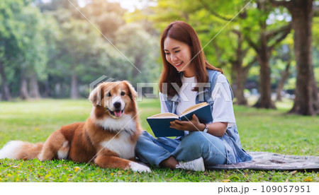 公園で犬と一緒に本を読んでいる若い女性　AI生成画像 109057951