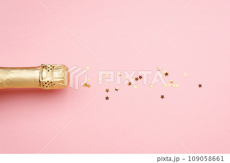 Champagne bottle with confetti stars on color background, space for text Champagne bottle with confetti stars on color background, space for text 109058661