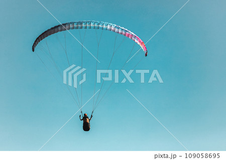 Paraglider in the sky. The sportsman flying on a paraglider. 109058695