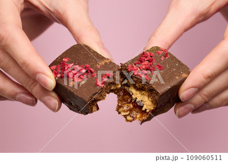 Woman's hands breaking vegan chocolate bar with dried fruits 109060511