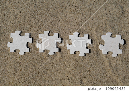 Four 4 wooden white puzzles copy space for your text on sandy beach. Summer vacation and holiday business travel concept. Jigsaw on the beach sand matching puzzle pieces together Template Mock up for Four 4 wooden white puzzles copy space for your text on sandy beach. Summer vacation and holiday business travel concept. Jigsaw on the beach sand matching puzzle pieces together Template Mock up for 109063483