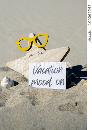 VACATION MOOD ON text on paper greeting card on background of beach chair lounge starfish summer vacation decor. Sandy beach sun. Holiday concept postcard. Travel VACATION MOOD ON text on paper greeting card on background of beach chair lounge starfish summer vacation decor. Sandy beach sun. Holiday concept postcard. Travel 109063547