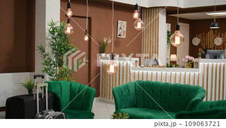 Elegant couch at hotel reception, empty front desk at registration area. Stylish modern five star resort with classy interior design featuring comfy seats and marble floors, expensive lounge area. 109063721