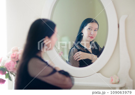 Young Asian woman looking in the mirror. Young Asian woman looking in the mirror. 109063979
